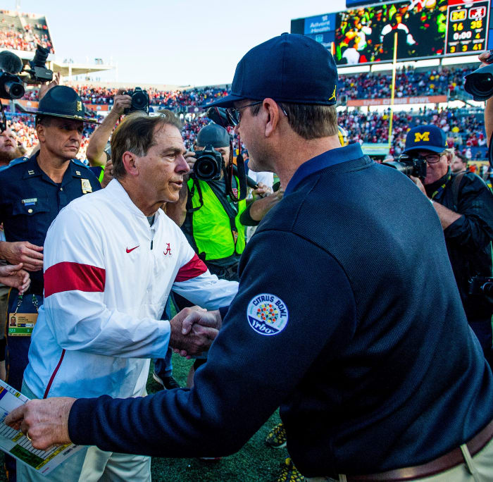 Nick Saban and Jim Harbaugh both lean forward as they shake hands